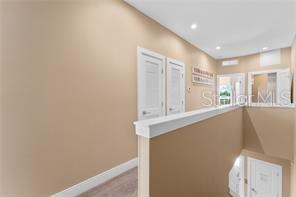 A hallway features beige walls, white trim, two closed doors, and a staircase railing — 3175 BRASILIA AVENUE, KISSIMMEE, FL