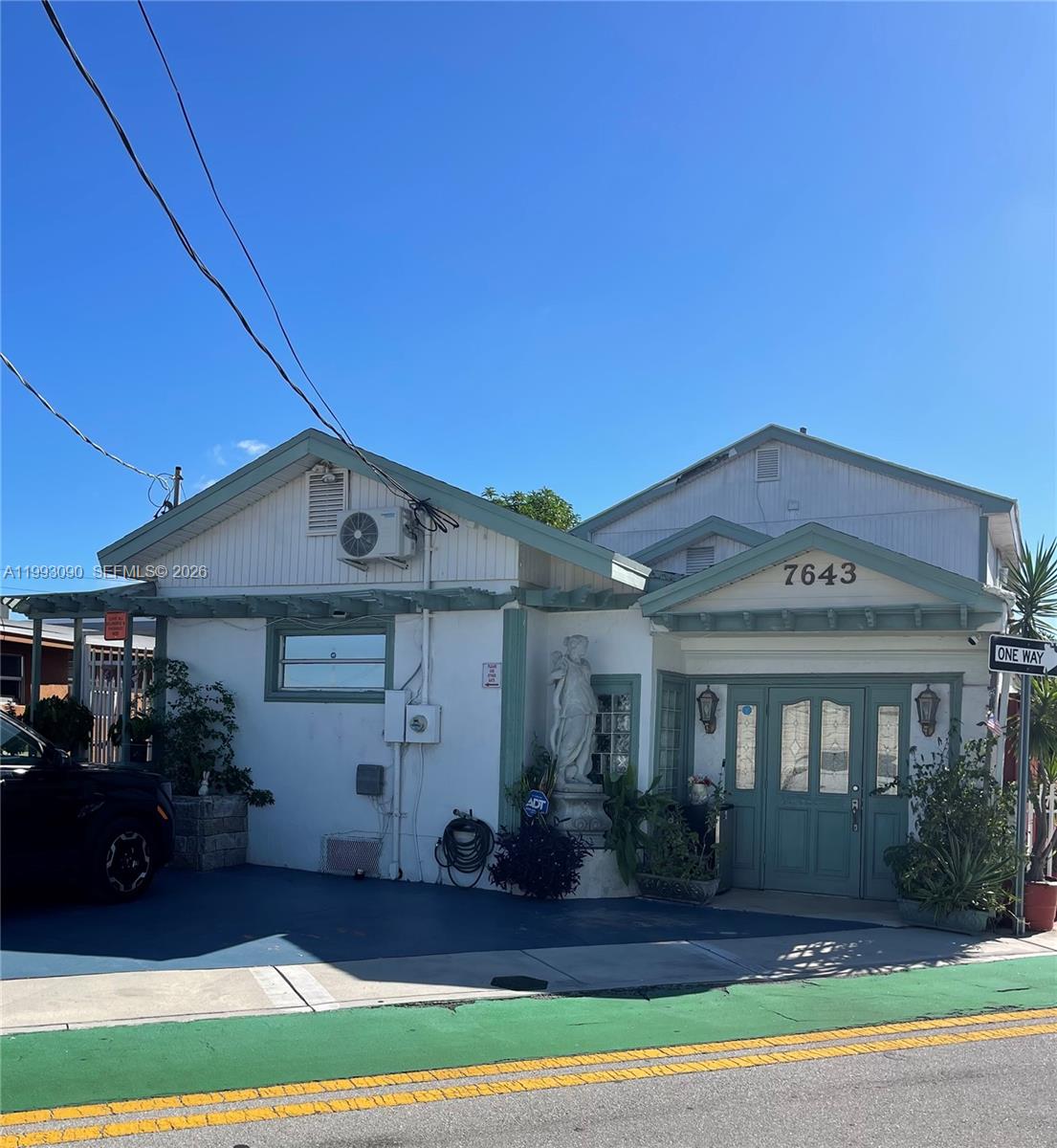 A single-story house with a blue-trimmed door, a statue, and a blue driveway — 7643 NW South River Dr, Medley FL 33166, MEDLEY, FL