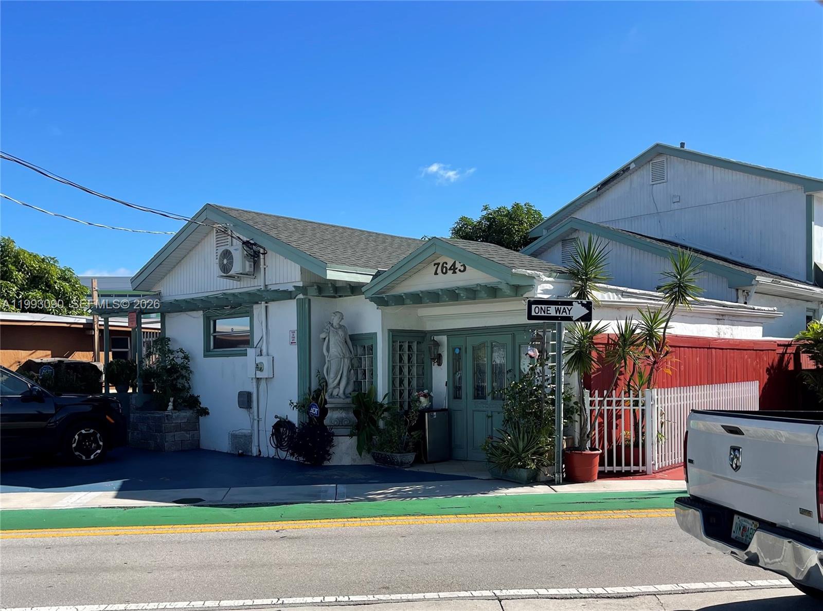 A white single-story building with green trim features a statue and a one-way sign — 7643 NW South River Dr, Medley FL 33166, MEDLEY, FL