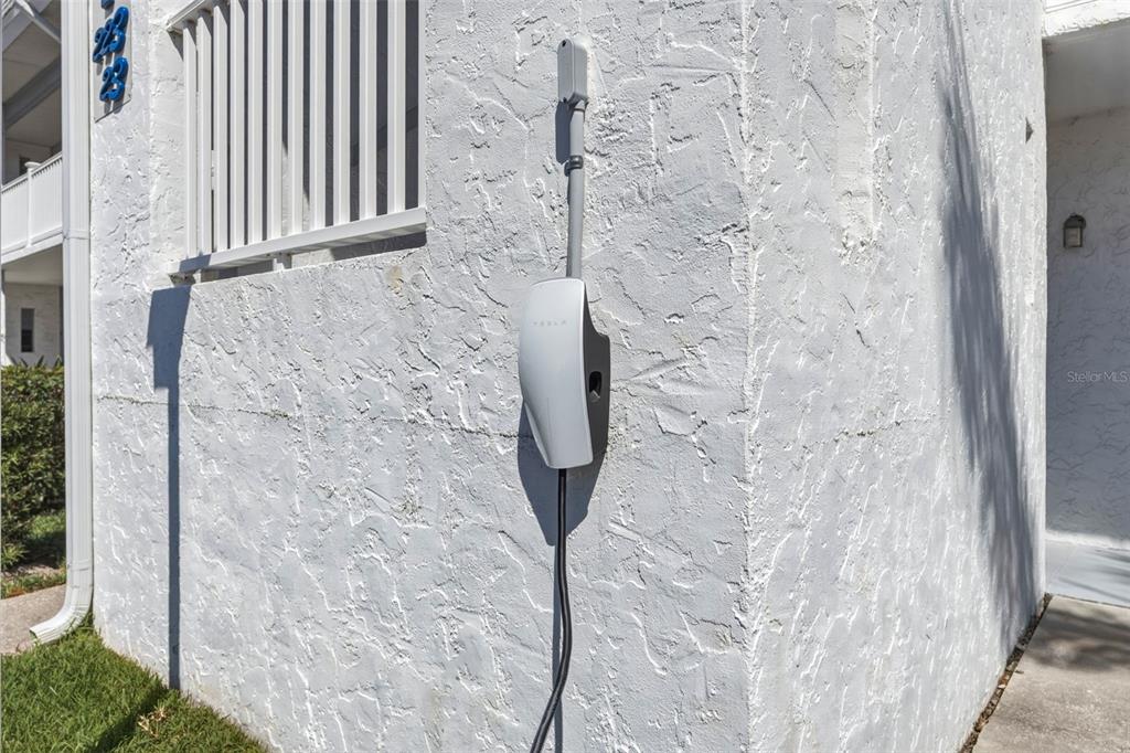 A Tesla wall-mounted electric vehicle charger is installed on the exterior stucco wall of a building — 22375 EDGEWATER DRIVE UNIT 224, PORT CHARLOTTE, FL