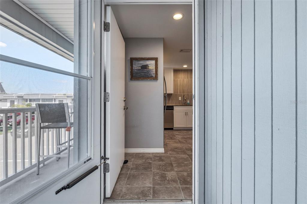 A view from a balcony through an open door into a kitchen with tiled floors — 22375 EDGEWATER DRIVE UNIT 224, PORT CHARLOTTE, FL