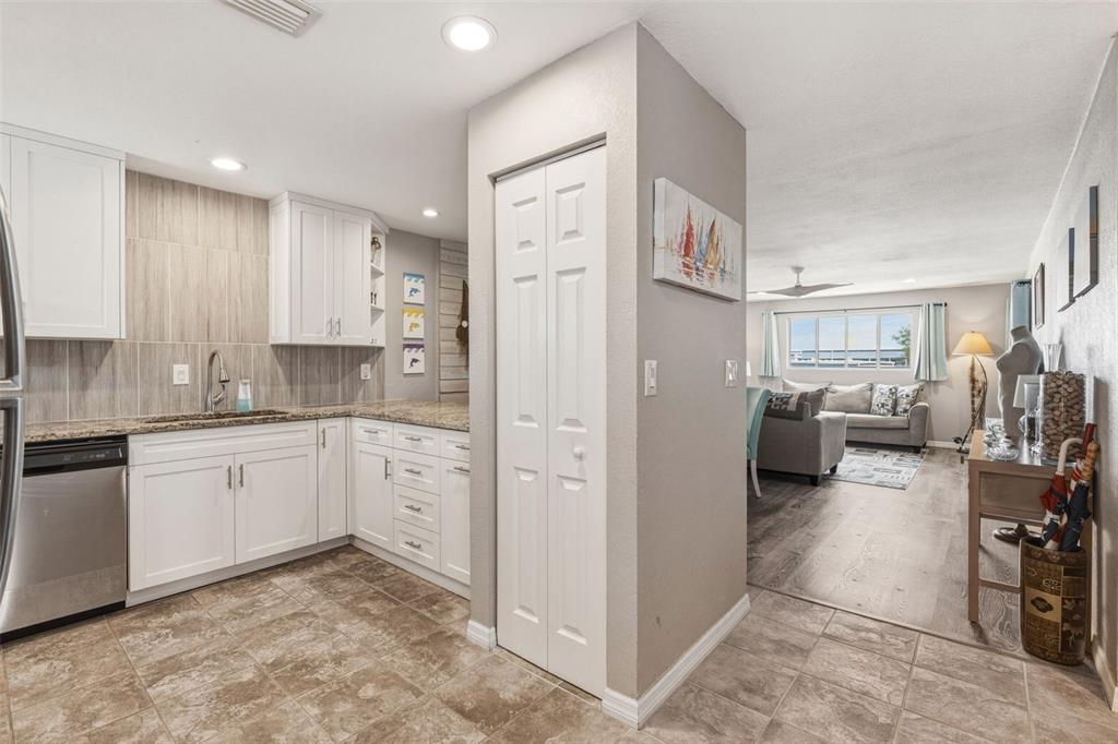 A kitchen with white cabinets and granite countertops opens into a living room area — 22375 EDGEWATER DRIVE UNIT 224, PORT CHARLOTTE, FL