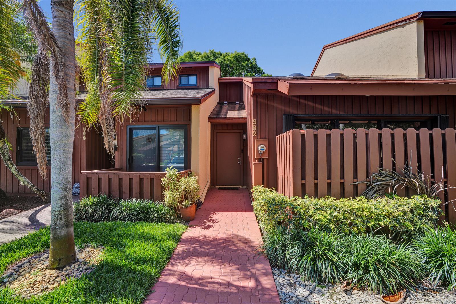 A brown townhouse exterior features a red brick walkway leading to a central front door — 456 SE 14th Street, Dania Beach FL 33004, DANIA BEACH, FL