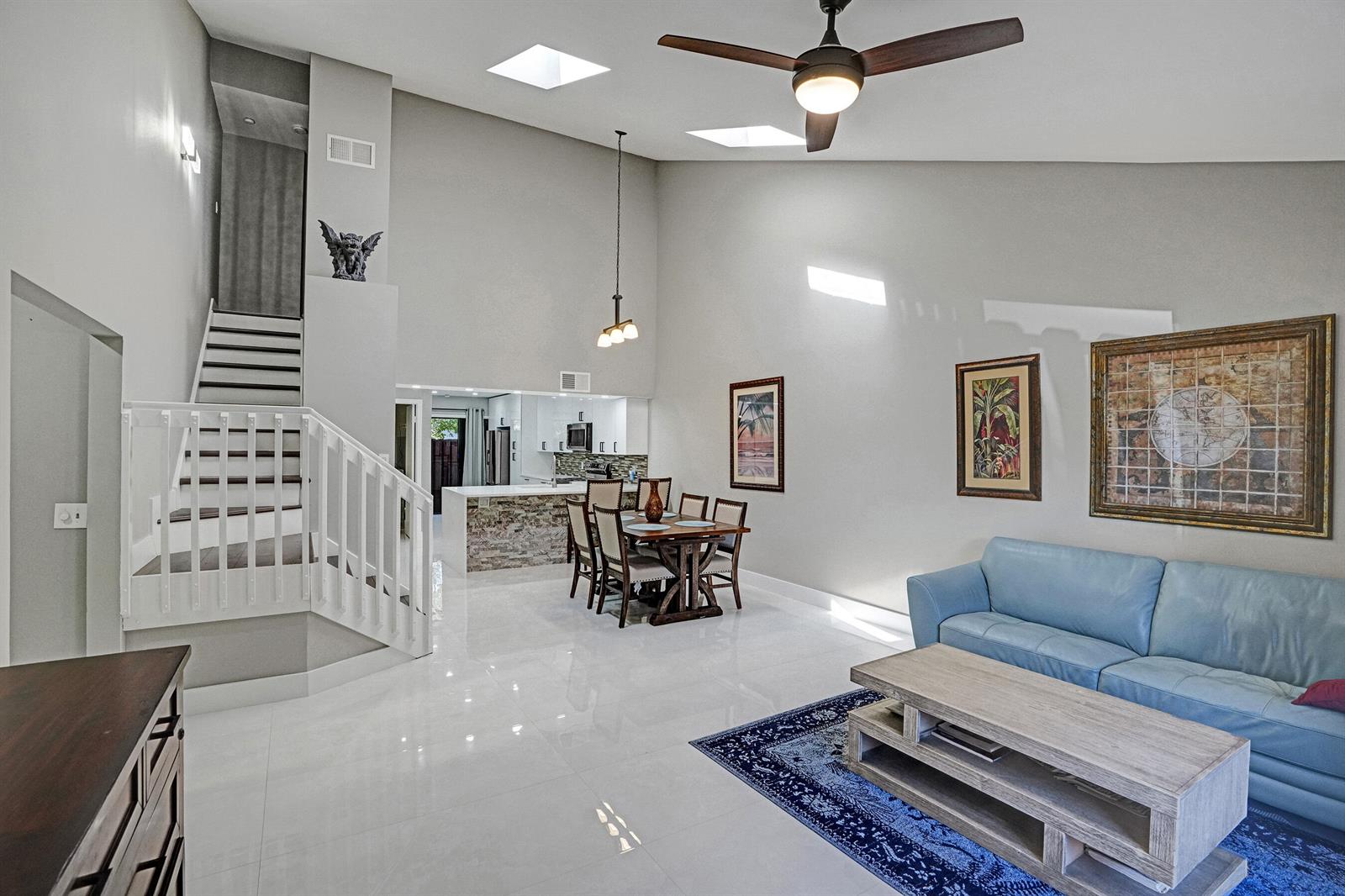 A living and dining area with high ceilings, tile floors, a staircase, and blue sofa — 456 SE 14th Street, Dania Beach FL 33004, DANIA BEACH, FL