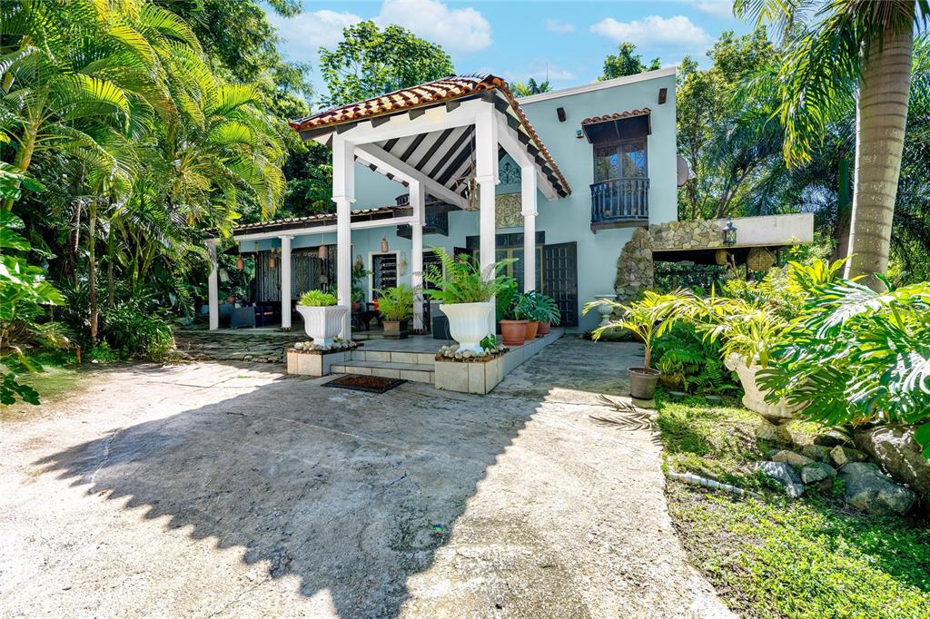 A light blue two-story house features a covered patio with white columns and lush landscaping — SR 310 km 0.8 LAS QUEBRADAS , HACIENDA TRES CASITAS, CABO ROJO, PR