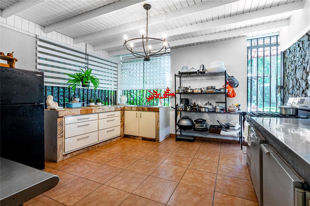 A kitchen features tiled floors, white cabinets, a metal shelving unit, and a black refrigerator — SR 310 km 0.8 LAS QUEBRADAS , HACIENDA TRES CASITAS, CABO ROJO, PR