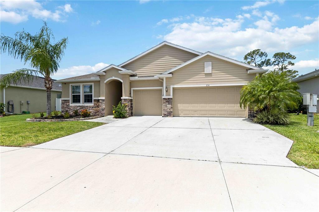 A single-story suburban house with a three-car garage and stone accents on the front facade — 214 TAPA PARISH RUN, BRADENTON, FL