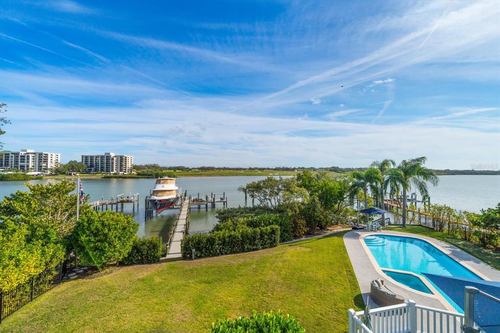 An aerial view of a backyard featuring a swimming pool, a private dock, and a boat — 430 ST ANDREWS DRIVE, BELLEAIR, FL