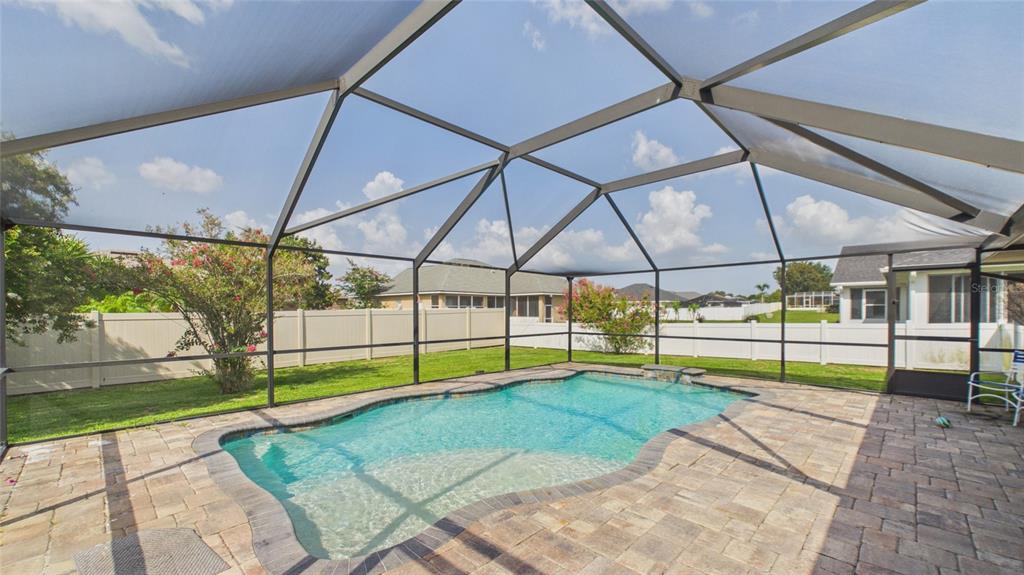 A swimming pool with a paver deck is enclosed by a screened lanai in a backyard — 315 LANCEOLATE DRIVE, WINTER HAVEN, FL