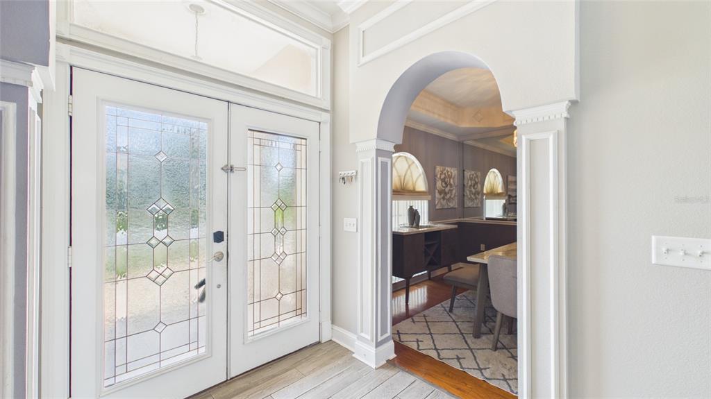 An entryway with a double glass door leads through an arched opening into a dining room — 315 LANCEOLATE DRIVE, WINTER HAVEN, FL