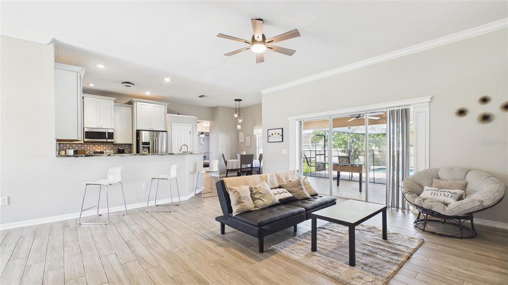 An open-concept living room and kitchen feature tile floors, white cabinetry, and sliding glass doors — 315 LANCEOLATE DRIVE, WINTER HAVEN, FL