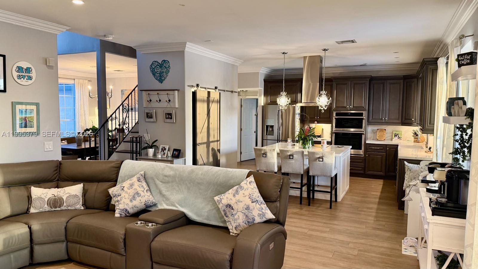 An open-concept living room and kitchen featuring dark cabinetry, a center island, and leather seating — 2386 SW 183rd Ter, Miramar FL 33029, MIRAMAR, FL