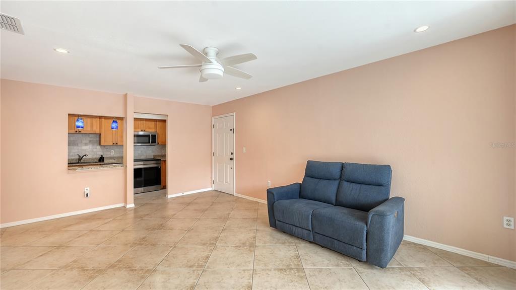 A living room with tile flooring, a blue loveseat, and an open view into the kitchen — 631 N ORANGE AVENUE UNIT 208, SARASOTA, FL