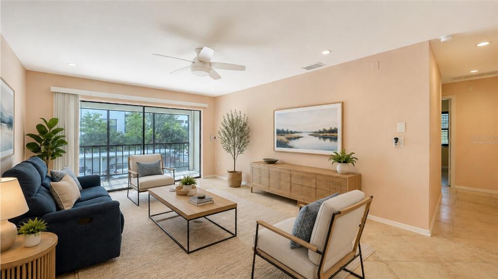 A living room features a blue sofa, two armchairs, a wooden console, and a balcony — 631 N ORANGE AVENUE UNIT 208, SARASOTA, FL