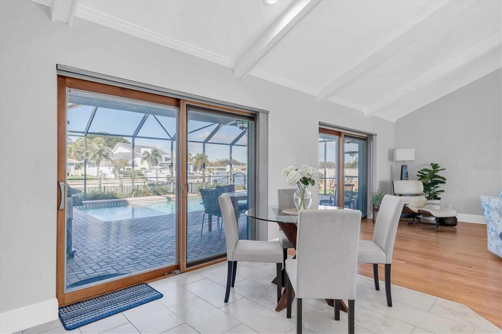 A dining area with a glass table and chairs overlooks a pool and canal — 4935 62ND AVENUE S, ST PETERSBURG, FL