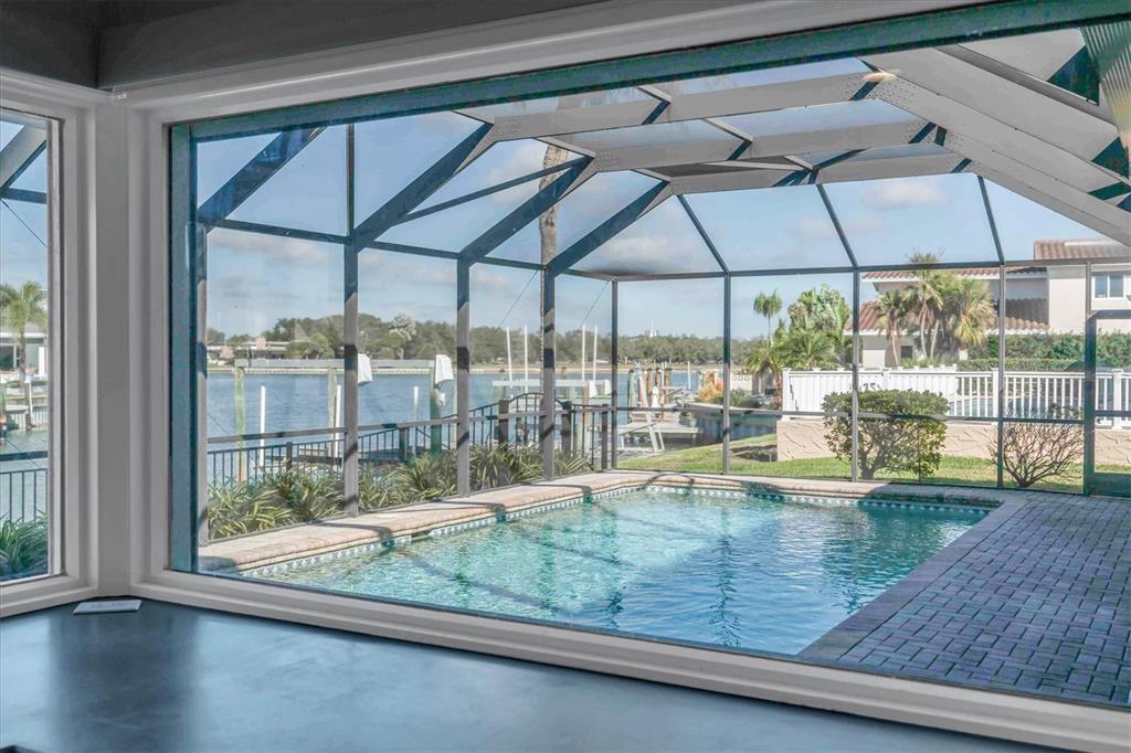 A view from inside looking out at a screened-in swimming pool overlooking a canal — 4935 62ND AVENUE S, ST PETERSBURG, FL