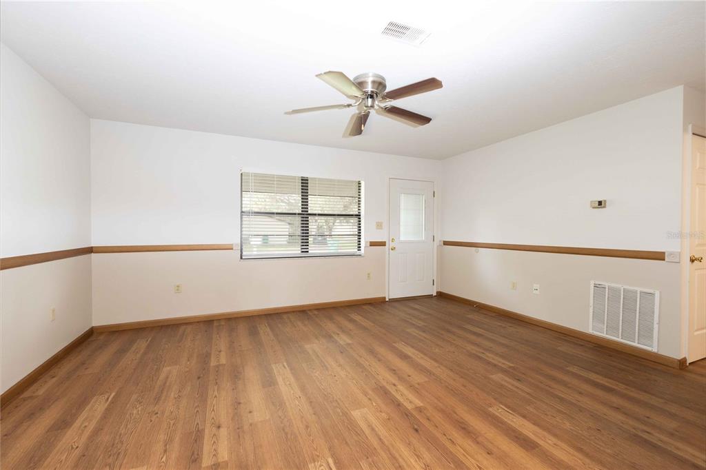 An empty room with wood-look flooring, white walls, a ceiling fan, and a window — 301 CURRY STREET, WILDWOOD, FL