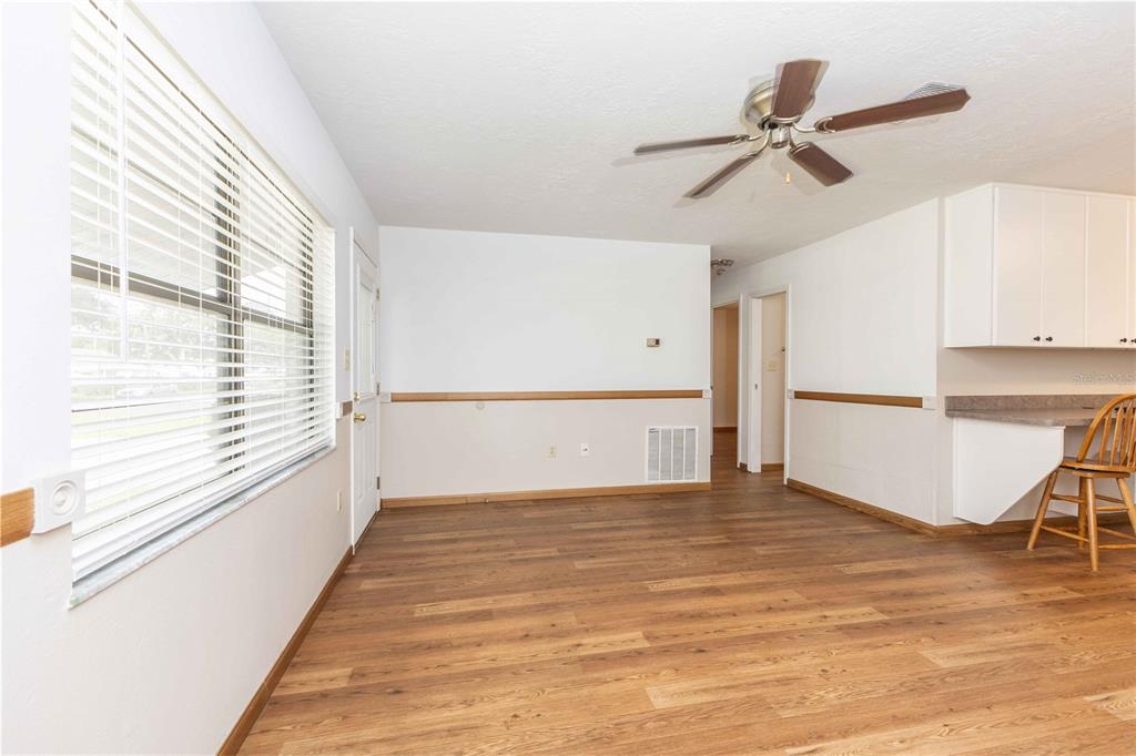 An empty room with wood-look flooring, a ceiling fan, and a kitchen counter area — 301 CURRY STREET, WILDWOOD, FL