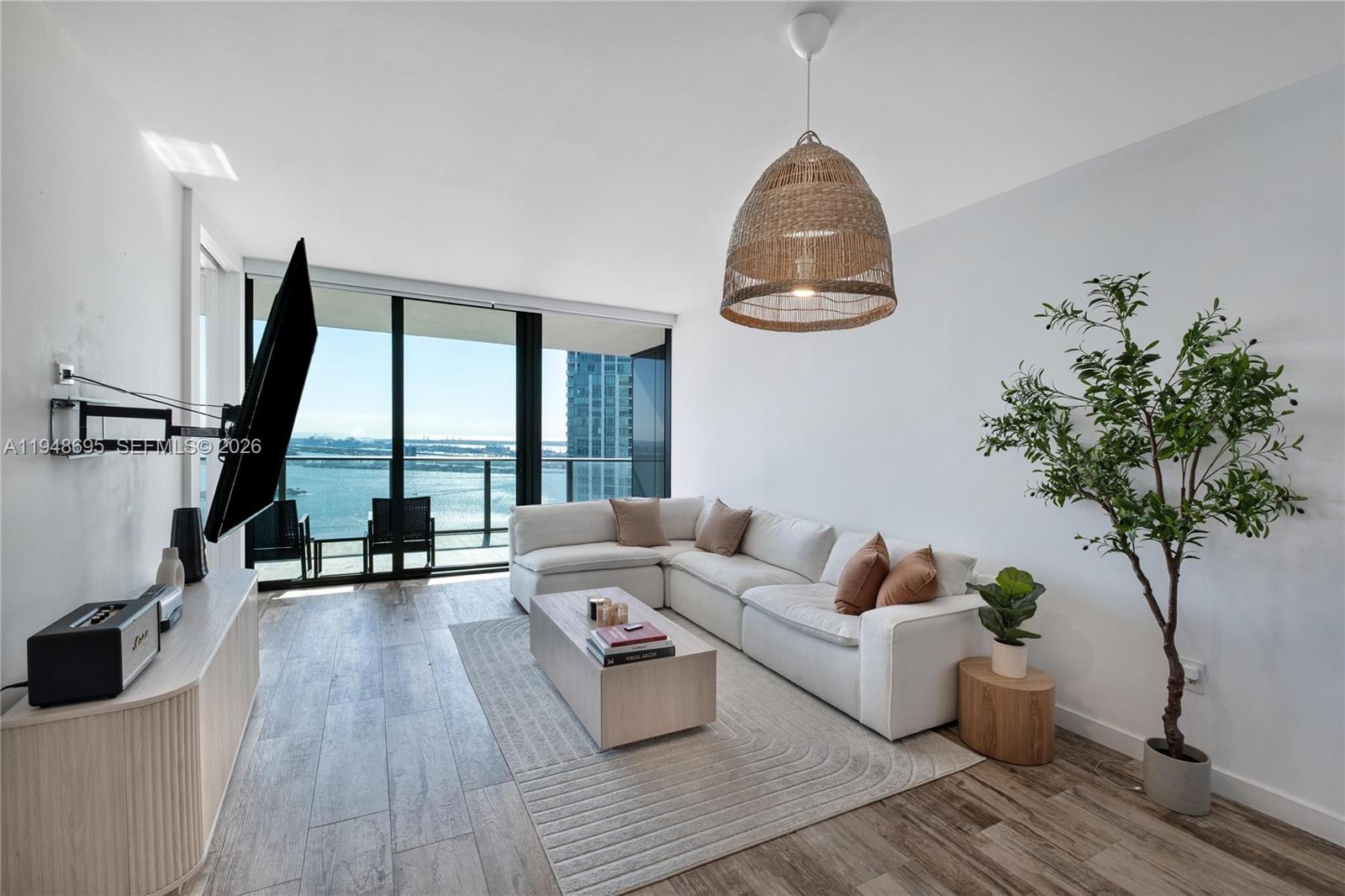 A modern living room features a white sectional sofa, wood coffee table, and balcony view — 650 NE 32nd St # 4306, Miami FL 33137, MIAMI, FL