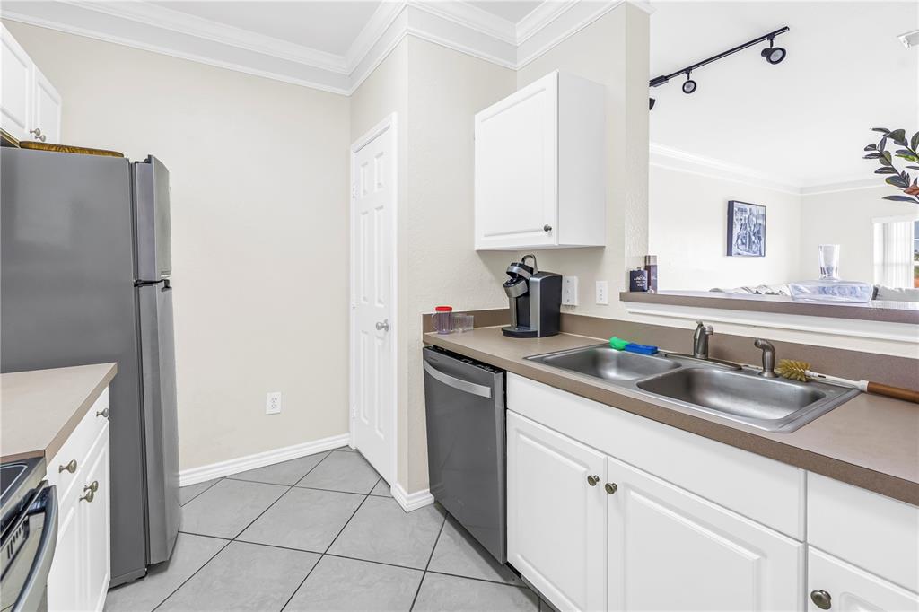 A kitchen features white cabinets, gray countertops, stainless steel appliances, and gray tile flooring — 4333 BAYSIDE VILLAGE DRIVE UNIT 320, TAMPA, FL