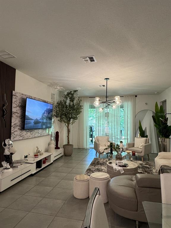 A modern living room features a marble-accented TV wall, tile flooring, and a globe chandelier — 4138 BABBLING BROOK WAY, KISSIMMEE, FL
