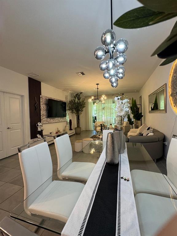 A dining area with a glass table and white chairs features a modern bubble chandelier — 4138 BABBLING BROOK WAY, KISSIMMEE, FL