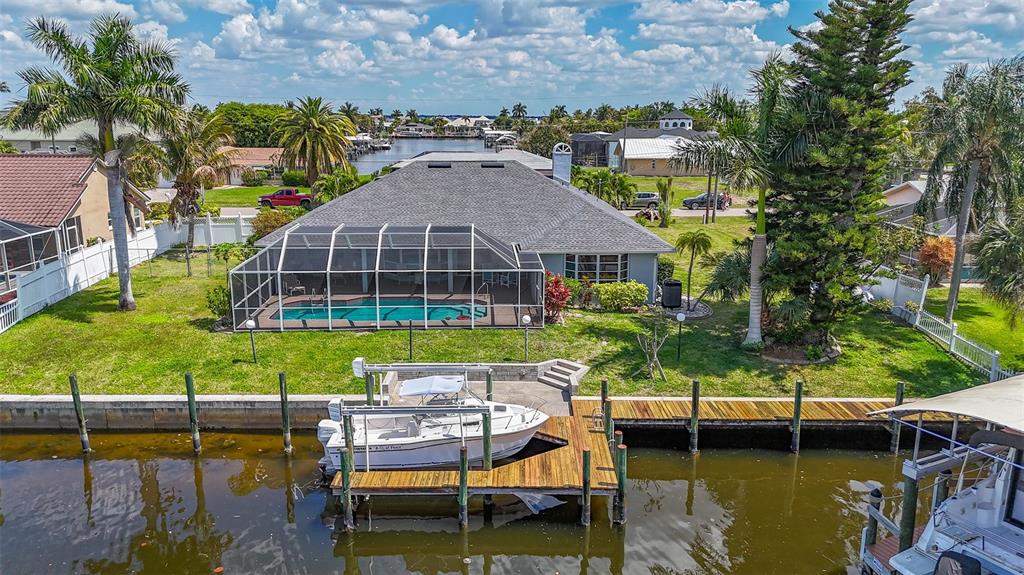 An aerial view shows a house with a pool enclosure, a dock, and a boat — 3316 SE 19TH PLACE, CAPE CORAL, FL