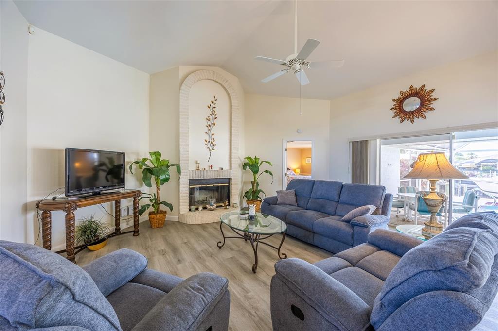 A living room features blue sofas, a glass coffee table, and a brick fireplace alcove — 3316 SE 19TH PLACE, CAPE CORAL, FL