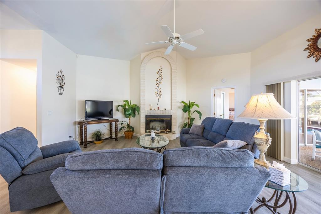 A living room features a fireplace, a ceiling fan, and blue upholstered furniture — 3316 SE 19TH PLACE, CAPE CORAL, FL