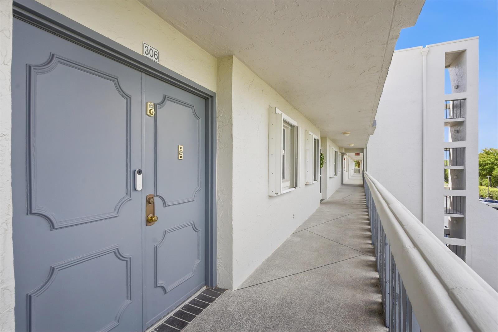 An exterior view of a gray apartment door with a doorbell camera on a walkway — 3286 Arcara Way # 306, Lake Worth FL 33467, LAKE WORTH, FL