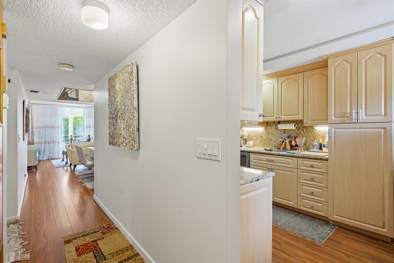 A hallway leads from a kitchen with light wood cabinets to a living area — 3286 Arcara Way # 306, Lake Worth FL 33467, LAKE WORTH, FL