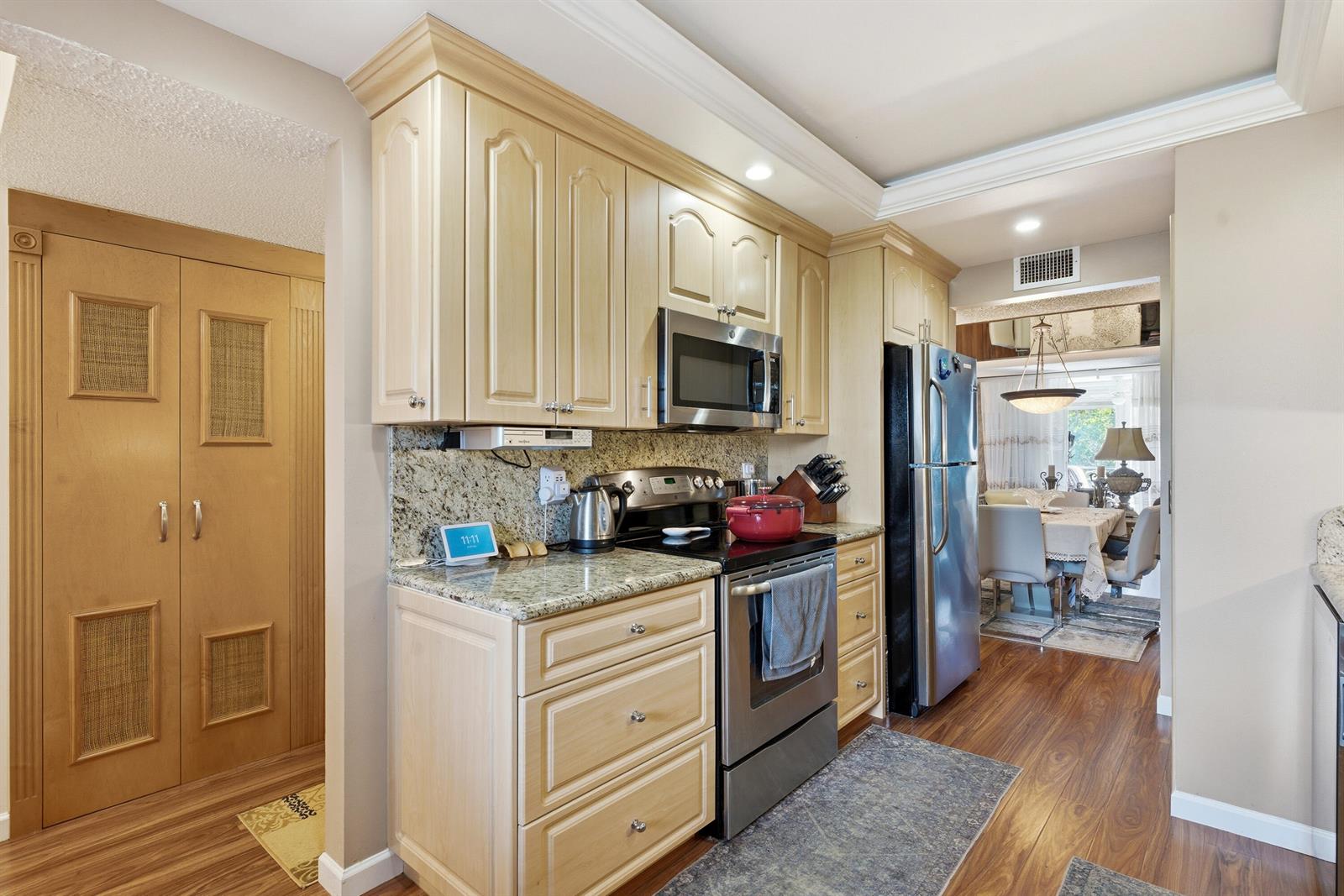 A kitchen features light wood cabinets, granite countertops, stainless steel appliances, and wood-look flooring — 3286 Arcara Way # 306, Lake Worth FL 33467, LAKE WORTH, FL