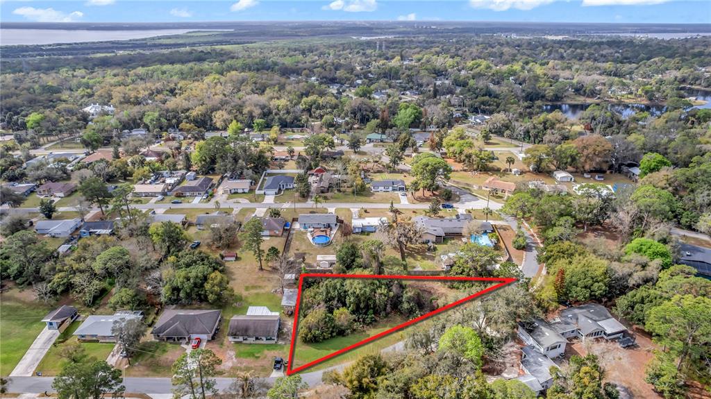 An aerial view shows a triangular, wooded vacant lot outlined in red within a residential neighborhood — 205 PLUMOSA ROAD, DEBARY, FL