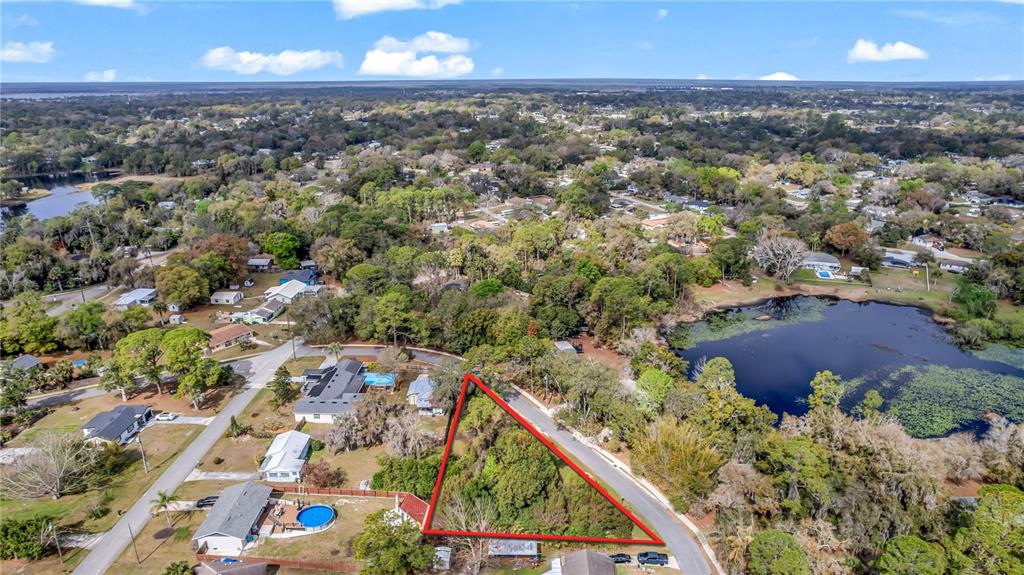 An aerial view shows a triangular vacant lot bordered by roads and nearby houses — 205 PLUMOSA ROAD, DEBARY, FL