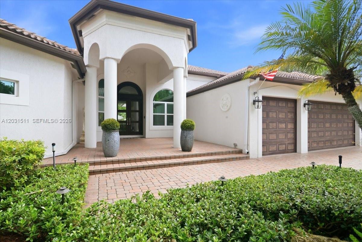 The exterior of a white house features a covered entryway with columns and a garage — 12160 NW 18th St, Plantation FL 33323, PLANTATION, FL