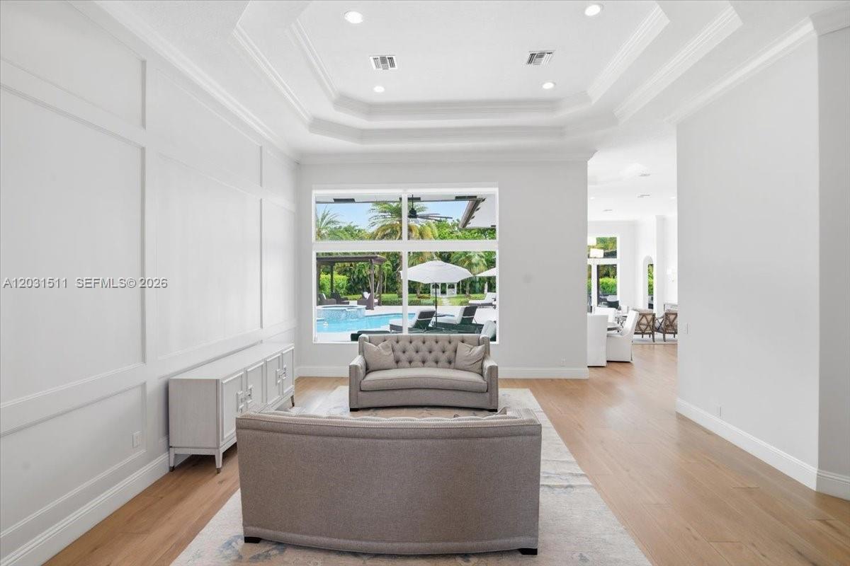 A living room with light wood floors, a tray ceiling, and a view of a pool — 12160 NW 18th St, Plantation FL 33323, PLANTATION, FL