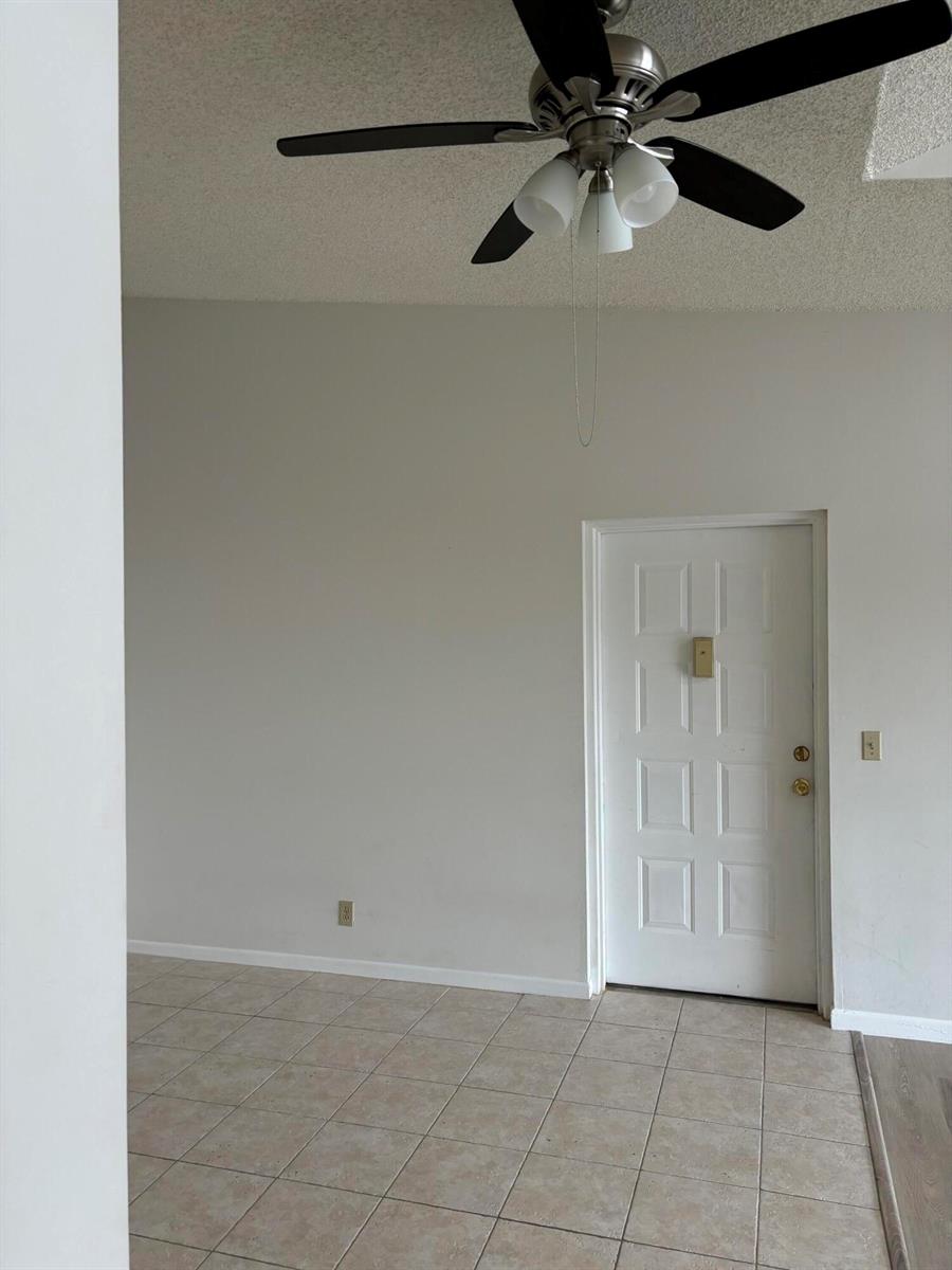 A room with a ceiling fan, tiled floor, and a white door — 207 Foxtail Drive # E3, FL 33415, FL