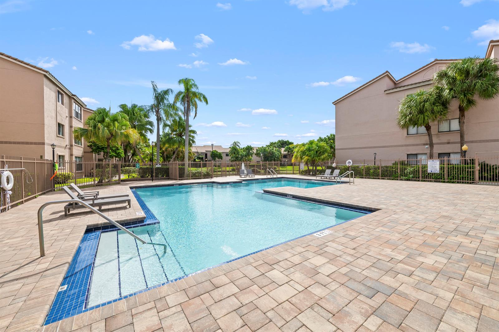 An outdoor swimming pool with a shallow entry area surrounded by a paved deck and buildings — 2736 S University Drive # 1104, Davie FL 33328, DAVIE, FL