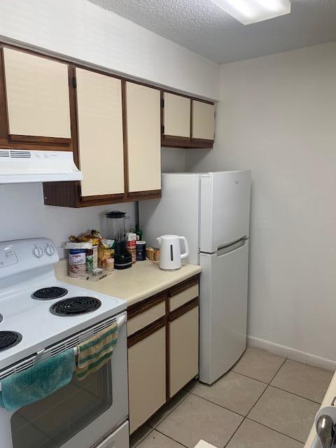 A kitchen features white appliances, light-colored cabinets with dark trim, and beige tiled flooring — 2736 S University Drive # 1104, Davie FL 33328, DAVIE, FL