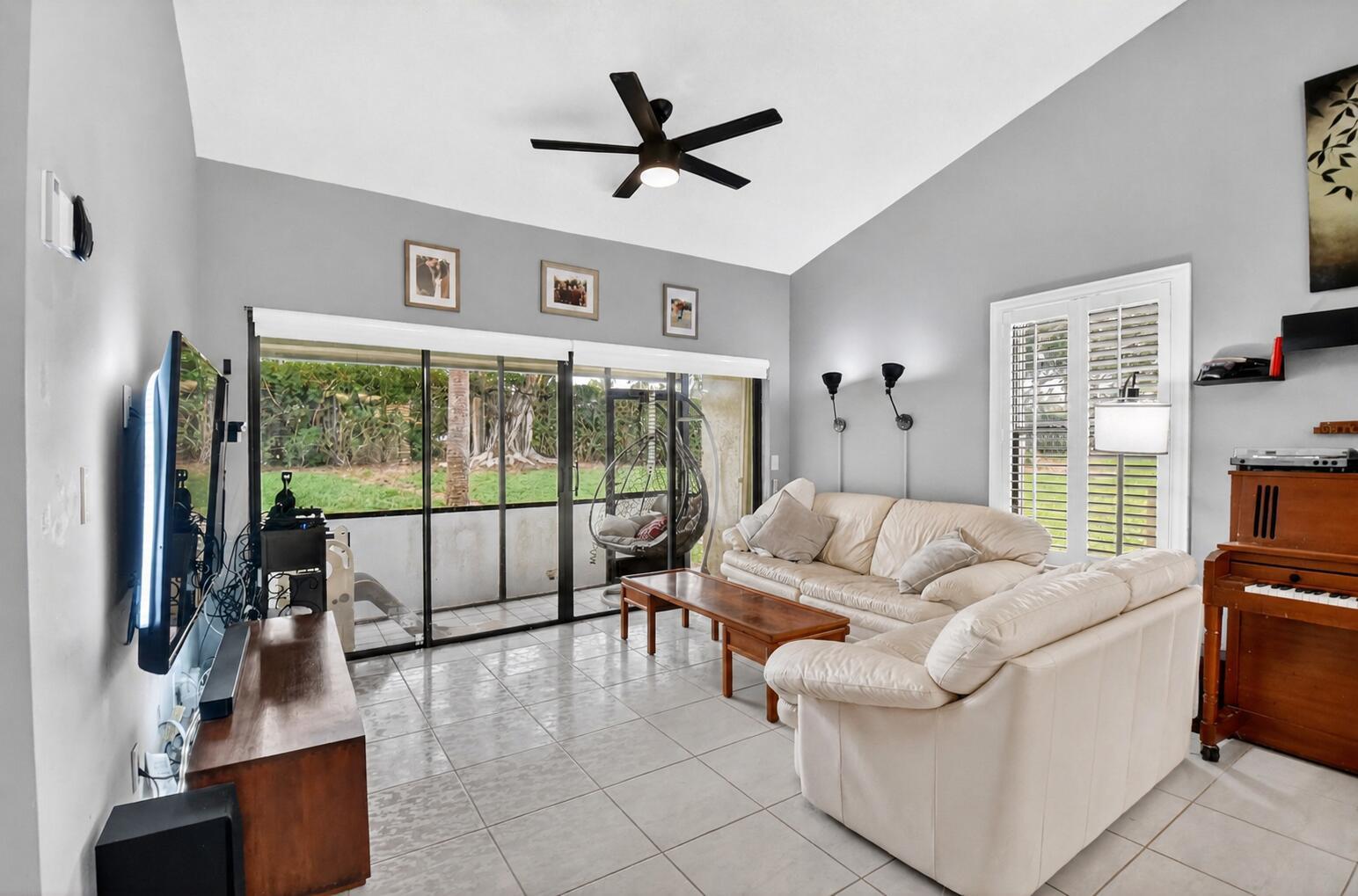 A living room with light gray walls, tile flooring, a white sofa, and sliding glass doors — 14 Via De Casas Sur # 104, Boynton Beach FL 33426, BOYNTON BEACH, FL