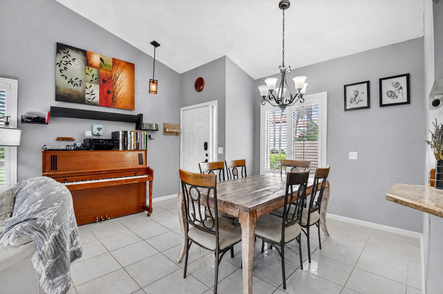 A dining room with a wooden table, chairs, and an upright piano on tiled floors — 14 Via De Casas Sur # 104, Boynton Beach FL 33426, BOYNTON BEACH, FL