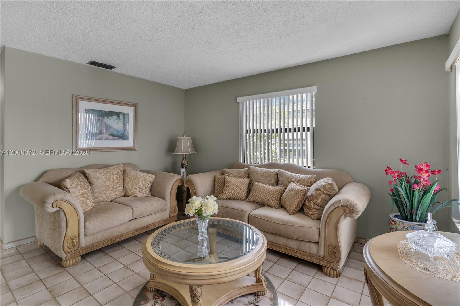A living room features beige sofas, a glass-topped coffee table, and light-colored tile flooring — 6770 SW 15th St, Miami FL 33144, MIAMI, FL
