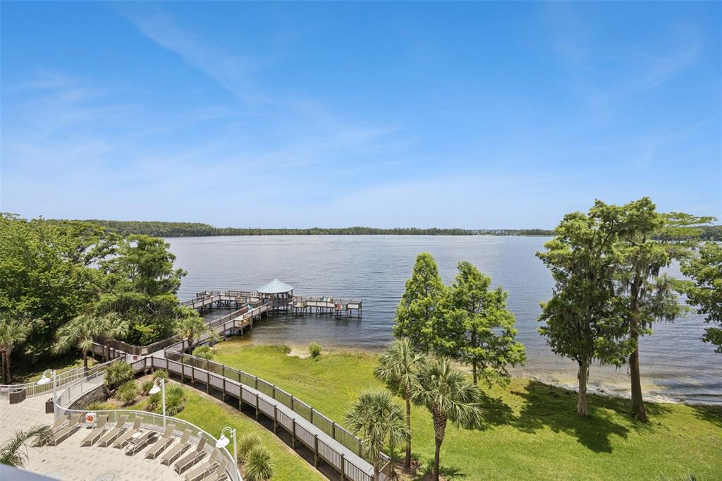 A high-angle view of a lake with a wooden pier and a paved walkway — 13427 BLUE HERON BEACH DRIVE UNIT 301, ORLANDO, FL