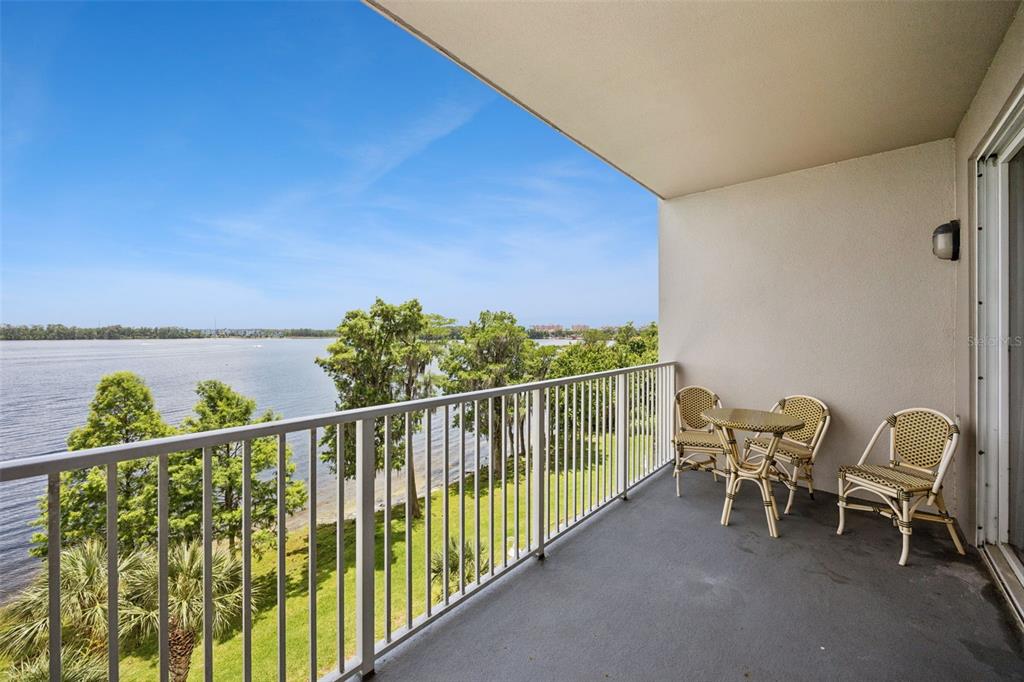 A balcony with a table and chairs overlooks a lake and trees — 13427 BLUE HERON BEACH DRIVE UNIT 301, ORLANDO, FL