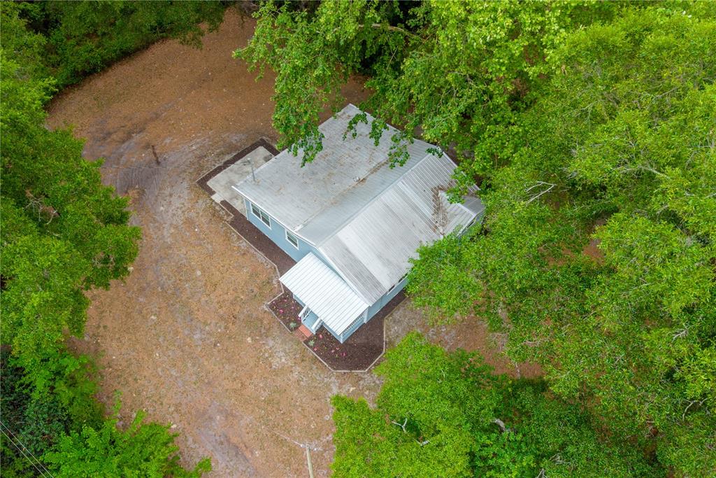 An aerial view shows a small house with a metal roof surrounded by dense trees — 16619 NW STATE ROAD 45, HIGH SPRINGS, FL