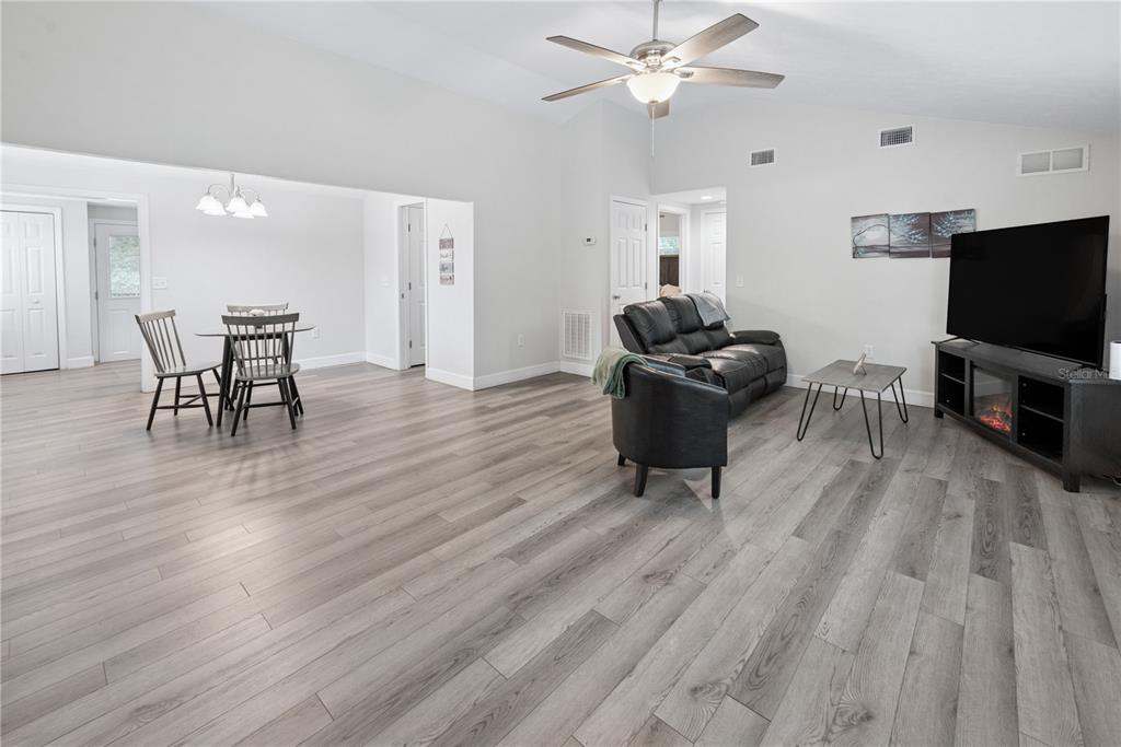 A living room and dining area with light wood-look flooring and a vaulted ceiling — 16619 NW STATE ROAD 45, HIGH SPRINGS, FL