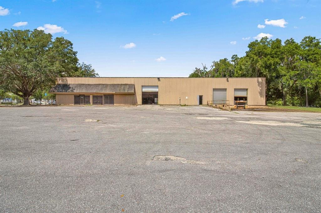 A single-story industrial warehouse building with a large asphalt parking lot in front — 1031 NE 16TH STREET, OCALA, FL