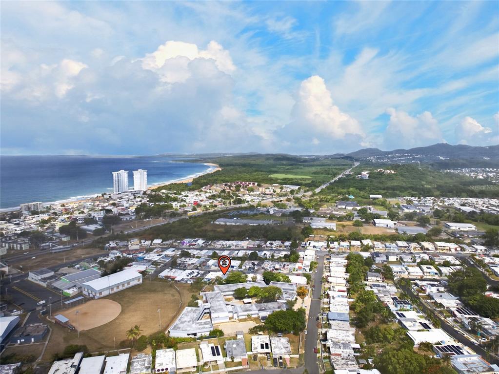 An aerial view shows a residential neighborhood near a coastline with a marked property location — C10 CALLE 5, LUQUILLO, PR