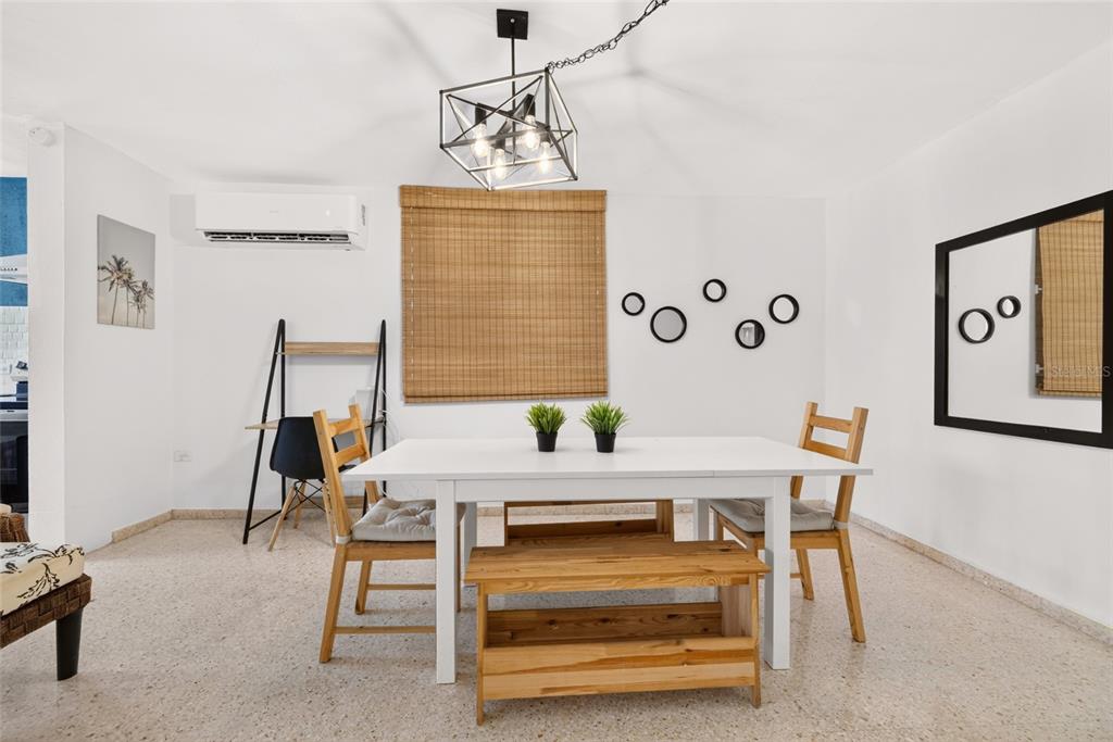 A dining room features a white table, wooden chairs, a bench, and a geometric light fixture — C10 CALLE 5, LUQUILLO, PR
