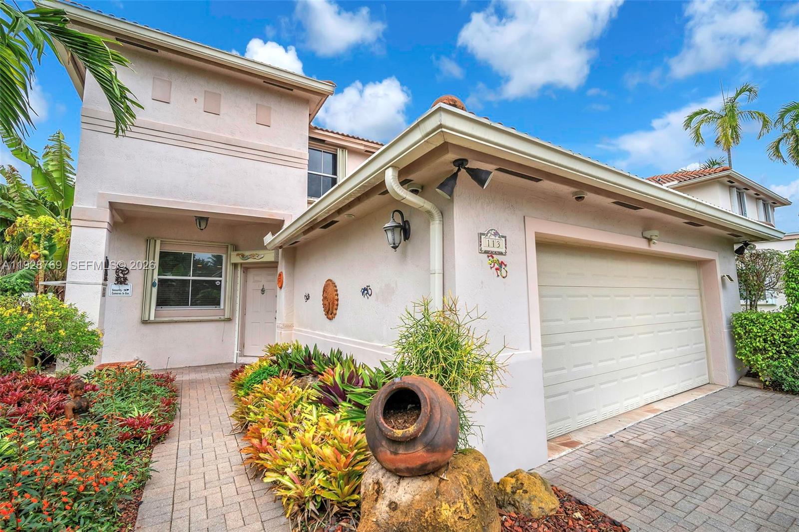 A two-story house with a beige stucco exterior, a single-car garage, and a landscaped walkway — 113 NW 73rd Ter, Plantation FL 33317, PLANTATION, FL